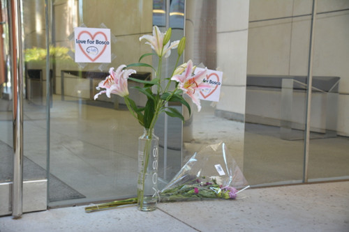 中国侨网出事的南加大文理学院Seeley Mudd科学大楼侧门前方纪念曾晓峰的花束还在，更有人在玻璃门上贴上图示，爱心外上写有“Love for Bosco”。（美国《世界日报》/吴佩甄 摄）