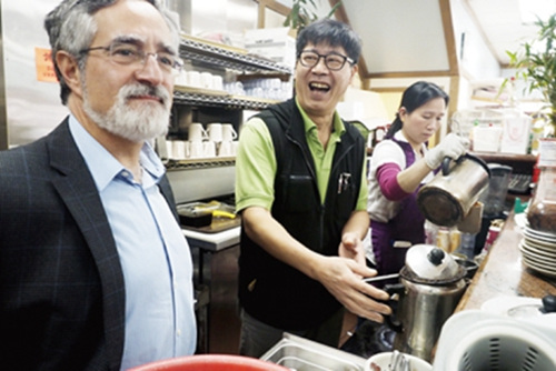 中国侨网“永兴饼家”老板陈永兴（中）向佩斯金（左）示范港式奶茶作法。（美国《世界日报》/关文杰 摄）