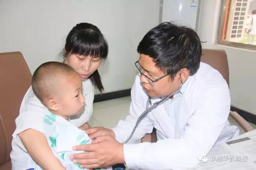 中国侨网心内科医生王正斌(右一)正为一名儿童听诊。(《非洲华侨周报》/申倩文 摄)