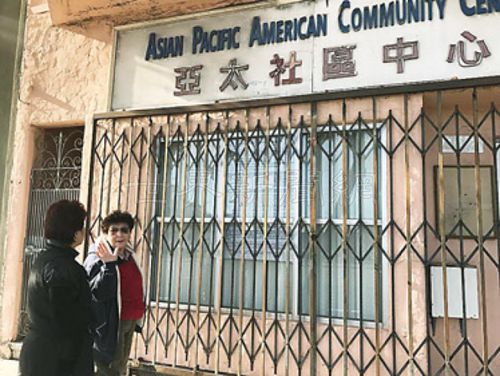 中国侨网谷亚太中心已搬走但招牌仍在。陈美玲(左二)与街坊走过,才发现铁闸后贴上市府公告,指该地点已被申请改为大麻诊所。(美国《世界日报》/李秀兰 摄)