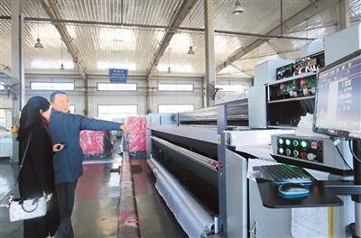中国侨网图为施乾平（右）在工厂向本报记者介绍他公司生产的工业打印机。张 兰摄