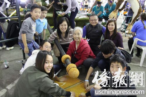 中国侨网赵奶奶（红衣）和她的一家三代在为金箍棒涂胶粘贴草籽。（美国《侨报》/高睿 摄）