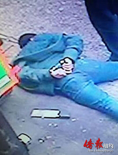 中国侨网黄明光被制服后趴在地上,行凶的菜刀扔在旁边 (视频截图)