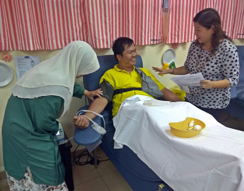 中国侨网林月兰与捐血者聊天，舒缓他的紧张心情。（马来西亚《星洲日报》）