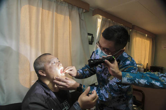 中国侨网两位军医检查患者咽部情况。