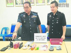 中国侨网岑振强展示起获的赌具。右是怡保刑事调查组警官邓惟亮。(马来西亚《光明日报》)