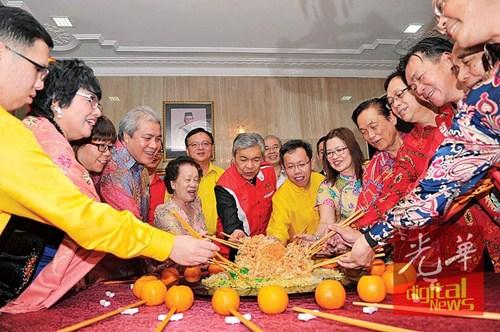 中国侨网阿末扎希与砂拉越州人联党主席沈桂贤（右6）等人，在新春团拜上一起捞生。（马来西亚《光华日报》）