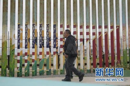 中国侨网2月6日，在墨西哥蒂华纳，居民从美墨边境墙前走过。新华社记者淡航摄