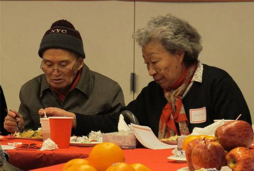 中国侨网吴玉梅(右)悉心照顾患阿兹海默症老伴吃饭。(美国《世界日报》/高梦梓 摄)