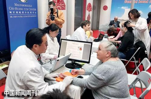 中国侨网2017年1月21日,在匈牙利布达佩斯举行的“中国春”欢乐春节活动现场,陈震(左一)为当地民众义诊。图|受访者提供