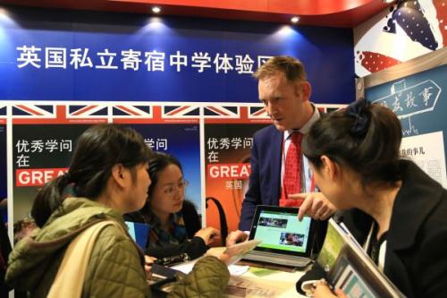 中国侨网工作人员在2013中国国际教育展上,为中国学生介绍英国私立寄宿中学的招生情况。新华社发