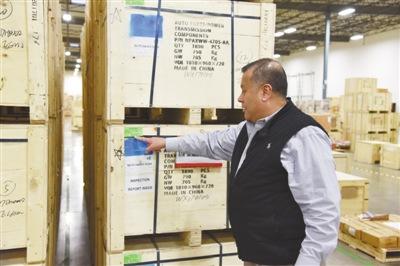 中国侨网在万向美国公司总部仓库，公司员工赫苏斯介绍从中国运来的货物。记者 章念生摄