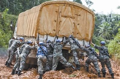 中国侨网中国赴利比里亚维和部队运输分队官兵在泥泞的道路上推车。穿梭在利比里亚的原始丛林中，中国蓝盔时常遭遇各种恶劣路况。 国防部维和事务办公室提供
