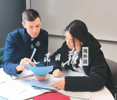 中国侨网贺楚萌（右）和外国同学在讨论如何修改论文