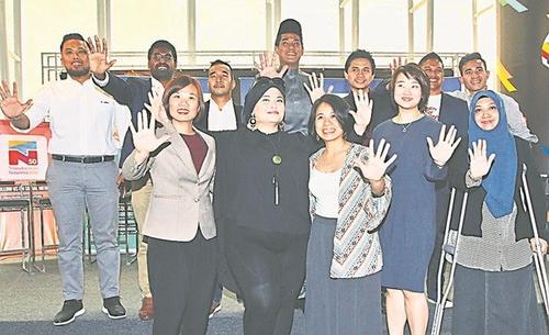 中国侨网凯里（后中）和11名TN 50大使展示象征TN 50的手势。前右起为艾占、黄颖欣、路易莎、莎拉和王玉玲，后左起为慕阿马、甘尼斯及查里夫，后右起为沙里韩旦、占米尔和陆菲。（马来西亚《光明日报》）