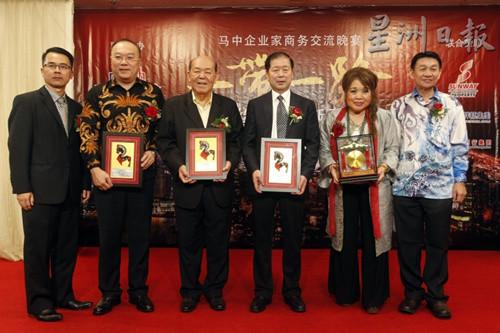 中国侨网符策勤（左二起）、吴德芳及李荣，从黄福来（左一）手中接过奖状后，合影留念。（马来西亚《星洲日报》）