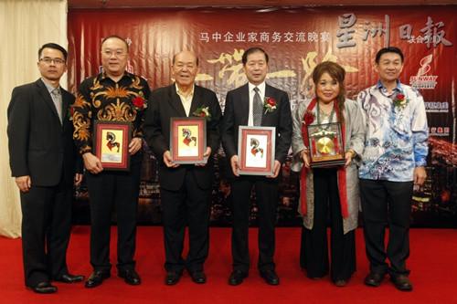中国侨网符策勤(左二起)、吴德芳及李荣,从黄福来(左一)手中接过奖状后,合影留念。(马来西亚《星洲日报》)