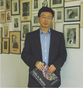 中国侨网蒋晓毅教授在系办公室内。他背后墙上的照片,是多名为系、校科研发展做出突出贡献的校友,其中也有多名莱布尼茨奖获得者。(《欧洲时报》德国版/张乔楠 摄)
