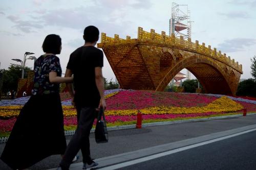 中国侨网5月10日，行人走过北京国家会议中心门前的“丝路金桥”景观作品。该会议中心为“一带一路”国际合作高峰论坛举办地之一。(路透社)