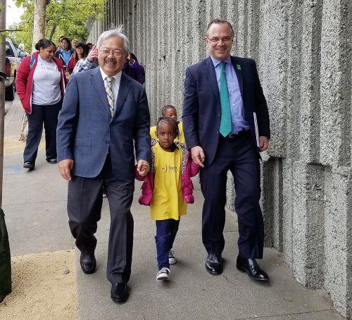 中国侨网旧金山市长李孟贤（左）和公共土地信托城市公园主任贝纳普（右），带着一名儿童步行前往山顶公园。（美国《侨报》/市长李孟贤办公室提供）