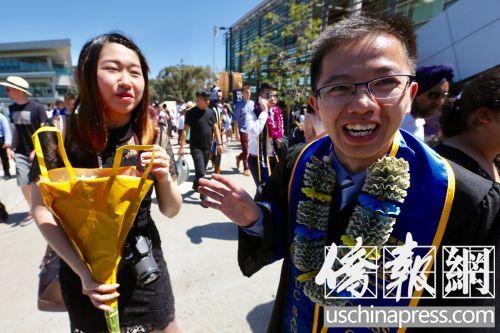 中国侨网圣地亚哥加大毕业生梁演铜（右）与室友（左）一起出席了毕业典礼。他脖子上的“美金花环”是今年毕业典礼上最时髦的毕业礼物，也是其室友亲手给他制作的毕业礼物。（美国《侨报》/邱晨 摄）
