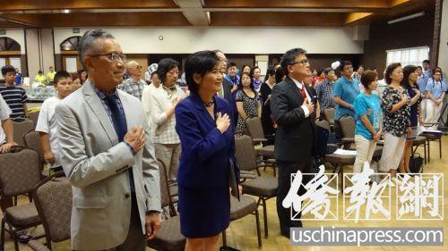 中国侨网(前排从左至右)唐廷赞、赵美心、江俊辉和上百名与会者向国旗致敬。(美国《侨报》/高睿 摄)