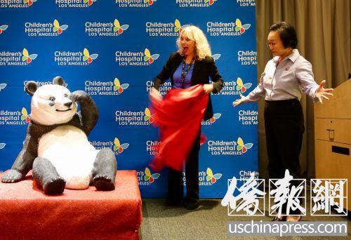 中国侨网程蒋佩琦（右）代表熊猫快餐接受儿童医院赠送的熊猫塑像。（美国《侨报》/邱晨 摄）