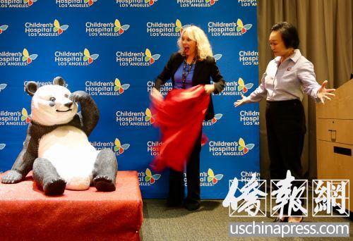 中国侨网程蒋佩琦(右)代表熊猫快餐接受儿童医院赠送的熊猫塑像。(美国《侨报》/邱晨 摄)