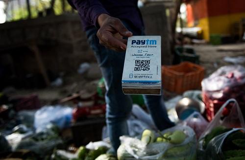 中国侨网资料图:在印度新德里街头一个菜摊,摊主手持Paytm二维码接受电子支付。 新华社记者 毕晓洋 摄