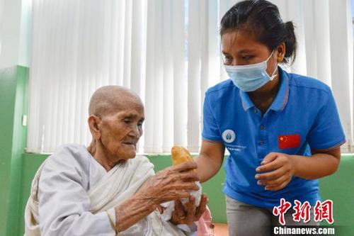 中国侨网图为柬埔寨志愿者珍珠为老奶奶买来面包。　洪坚鹏　摄