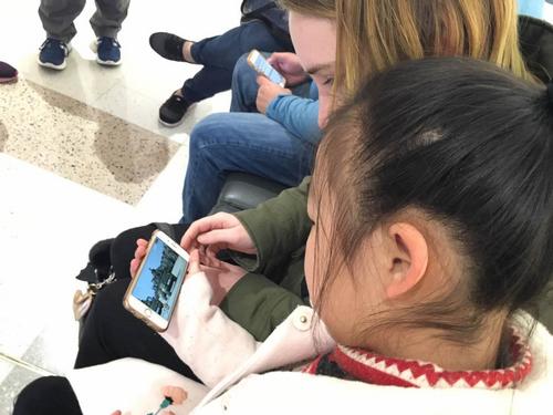 中国侨网华裔小女孩Pipi和澳洲姑娘Anny用手机浏览中国阅兵的图片。