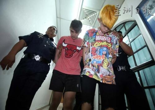 中国侨网染著金发的19岁被告梁忠兴，与20岁的冯凌舟，低着头被押致法庭面控，人名皆译音。（马来西亚《星洲日报》）