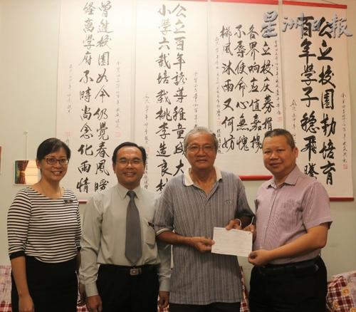 中国侨网张凤芳的丈夫刘东南（右二）代表梁金耀移交10万令吉作为公立华小建校经费。左起是副校长李佳珈、校长余振荣及冯家声（右一）。（马来西亚《星洲日报》）