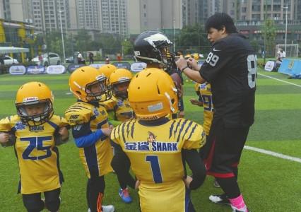 中国侨网薛荣神向小队员讲解美式橄榄球的要领。