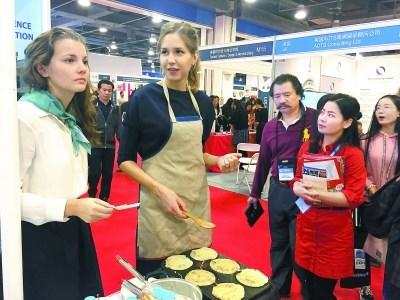 中国侨网俄罗斯展区的美少女化身小厨娘,现场摊起了俄罗斯薄饼。