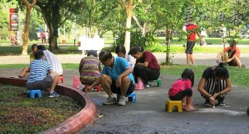 中国侨网无名男女老少义工,不分你我埋头清除地面上的烛泪。(马来西亚《星洲日报》)