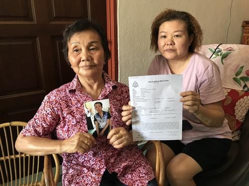 中国侨网纪亚燕（左）及叶慧蓉展示林训仲的照片和报案纸。（马来西亚《星洲日报》）