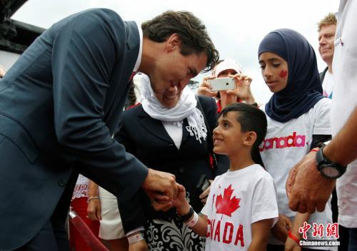 中国侨网资料图：加拿大总理特鲁多与叙利亚移民。