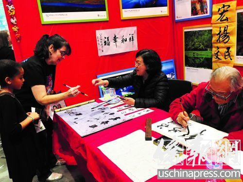 中国侨网吕梧鸣老人（右）展示书法。（美国《侨报》/毛苌子 摄）