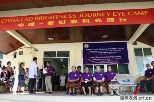 中国侨网部分已做完手术的患者8日在活动举行地万象玛霍索医院外等候复检。