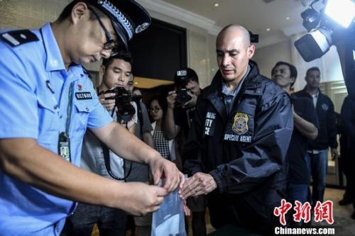 中国侨网资料图:中国警察向美国警察转交扣押的美籍逃犯个人物品.