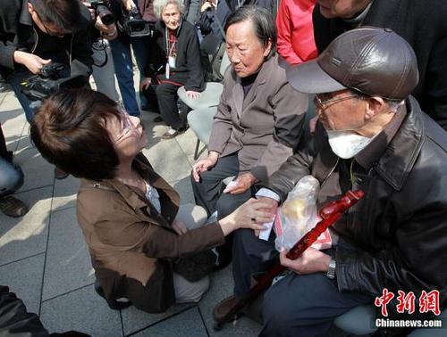 中国侨网资料图：来自日本铭心会南京访华团的团长松冈环（左）单膝跪地，在和南京大屠杀幸存者交谈。中新社发 泱波 摄