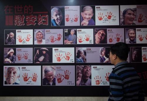 中国侨网资料图片：2016年12月10日，一名与会者在观看纪实画册《90位幸存慰安妇实录》首发现场展示的书中照片。新华社记者 罗晓光 摄