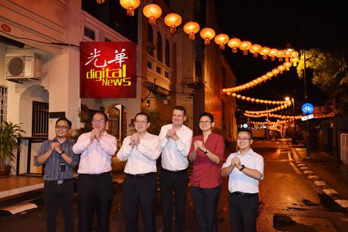 中国侨网林冠英等人在灯光照映下，一起给槟州民众拜早年。（马来西亚《光华日报》）