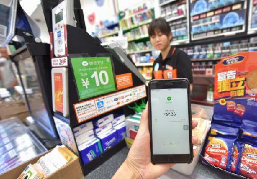 中国侨网资料图:一名顾客在香港7-Eleven便利店体验使用微信支付并获得优惠。(新华社)