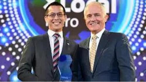 中国侨网华裔数学老师Eddie Woo(右)从谭保(左)手上接过“杰出澳人”奖杯。(墨市华厦微信公众号援引当地媒体)