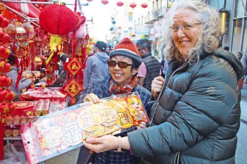 中国侨网许多非华裔的民众也在选购年货，拿着“福来旺到”的春联。(美国《世界日报》/李晗 摄)