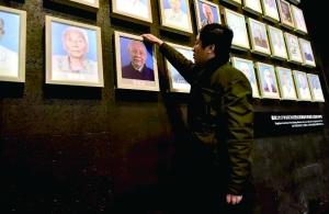 中国侨网纪念馆副馆长为老人的灯箱照片灭灯。