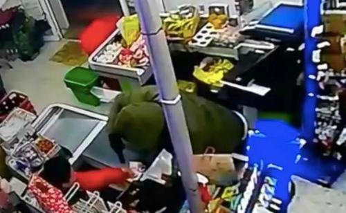 中国侨网监控录像拍下的持枪劫匪在收银台处。（西班牙《欧华报》）