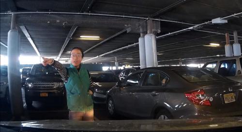 中国侨网华人女子霸占车位，挡在车前要求周乐骏开走。（美国《世界日报》）